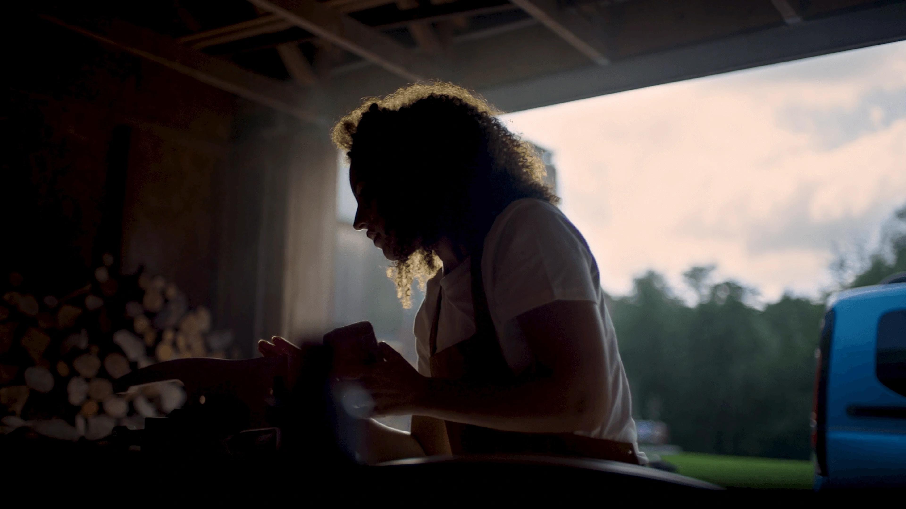 A screenshot from the 'As Versatile As You Are' Ford Tourneo Connect commercial directed by Davy Lazare. The image shows a lady in a workshop in the countryside, with the Ford Tourneo in the background.