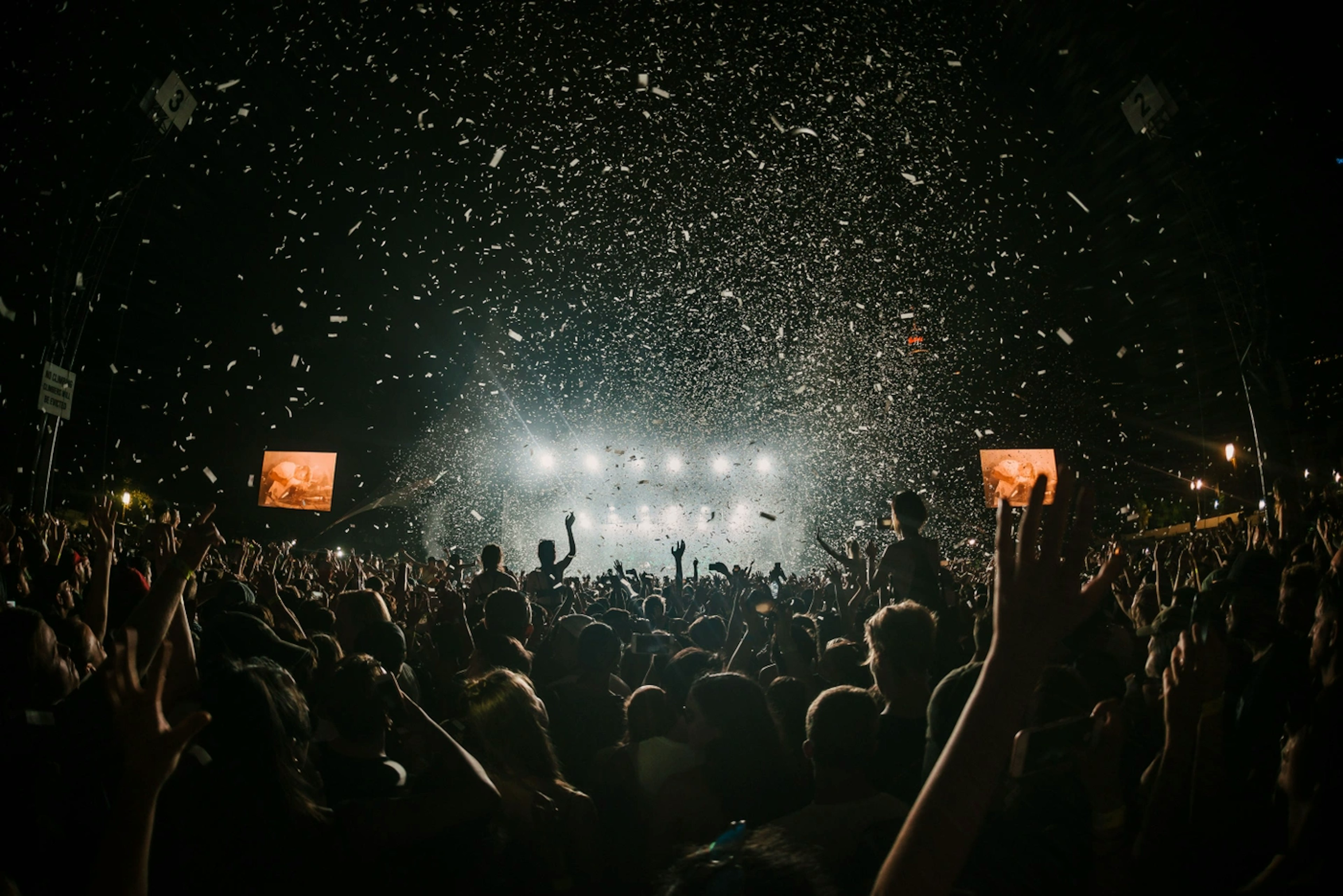 Cinemagraphic photo of a large group of people enjoying a rock concert with concert lights beaming down. Image by Danny Howe on Unsplash.